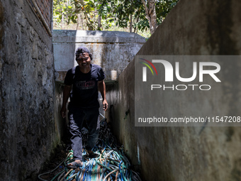 A man walks with a water hose as he directs it to his house during drought season in Selopamioro Village, Bantul Regency, Yogyakarta Provinc...