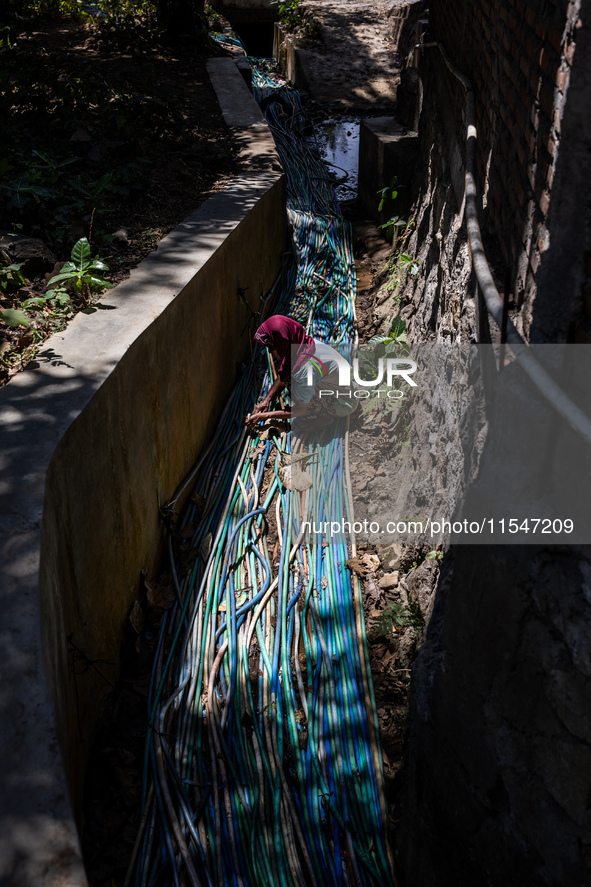 A woman connects a water hose to the only water source to her house during drought season in Selopamioro Village, Bantul Regency, Yogyakarta...