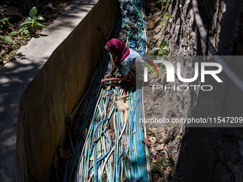 A woman connects a water hose to the only water source to her house during drought season in Selopamioro Village, Bantul Regency, Yogyakarta...