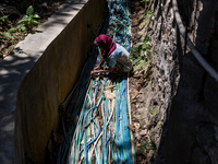 A woman connects a water hose to the only water source to her house during drought season in Selopamioro Village, Bantul Regency, Yogyakarta...