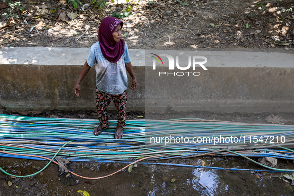 A woman stands at a water hose before she directs it to her house during drought season in Selopamioro Village, Bantul Regency, Yogyakarta P...