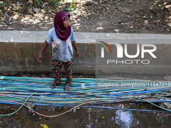 A woman stands at a water hose before she directs it to her house during drought season in Selopamioro Village, Bantul Regency, Yogyakarta P...