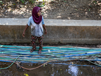 A woman stands at a water hose before she directs it to her house during drought season in Selopamioro Village, Bantul Regency, Yogyakarta P...