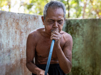 Sarjono (73), an elderly blind man, takes water from the only source of water by sucking it up and flowing it through a hose to his house du...