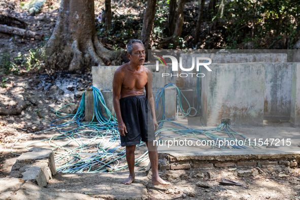 Sarjono (73), an elderly blind man, walks to connect a water hose to his house during the drought season in Selopamioro Village, Bantul Rege...