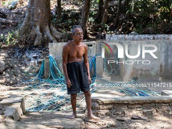 Sarjono (73), an elderly blind man, walks to connect a water hose to his house during the drought season in Selopamioro Village, Bantul Rege...