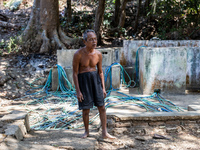 Sarjono (73), an elderly blind man, walks to connect a water hose to his house during the drought season in Selopamioro Village, Bantul Rege...