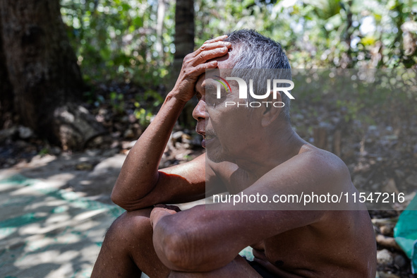 Sarjono (73), an elderly blind man, sits after connecting a water hose to the only water source to his house during the drought season in Se...