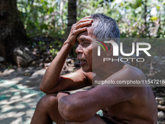 Sarjono (73), an elderly blind man, sits after connecting a water hose to the only water source to his house during the drought season in Se...