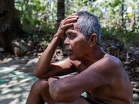 Sarjono (73), an elderly blind man, sits after connecting a water hose to the only water source to his house during the drought season in Se...