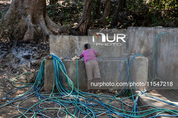 A woman connects a water hose to the only water source to her house during drought season in Selopamioro Village, Bantul Regency, Yogyakarta...