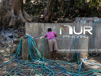 A woman connects a water hose to the only water source to her house during drought season in Selopamioro Village, Bantul Regency, Yogyakarta...