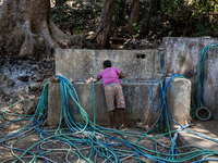 A woman connects a water hose to the only water source to her house during drought season in Selopamioro Village, Bantul Regency, Yogyakarta...