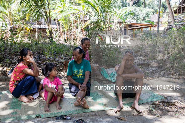 Residents fetch water from the only source by sucking it up and flowing it through a hose to their house during the drought season in Selopa...