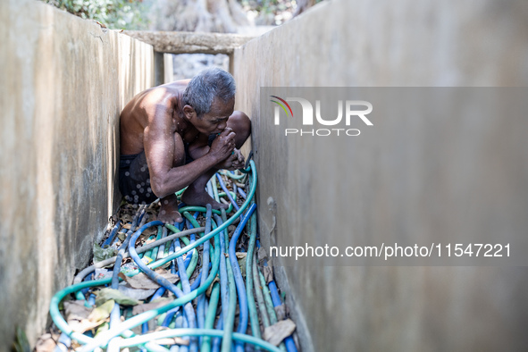 Sarjono (73), an elderly blind man, takes water from the only source of water by sucking it up and flowing it through a hose to his house du...