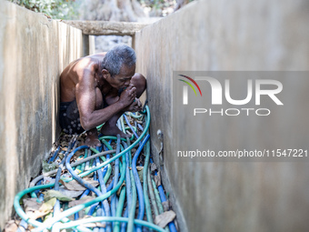 Sarjono (73), an elderly blind man, takes water from the only source of water by sucking it up and flowing it through a hose to his house du...