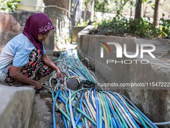 A woman connects a water hose to the only water source to her house during drought season in Selopamioro Village, Bantul Regency, Yogyakarta...