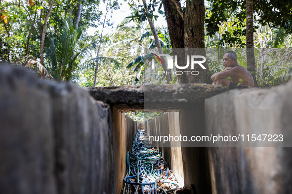 Sarjono (73), an elderly blind man, sits after connecting a water hose to the only water source to his house during the drought season in Se...