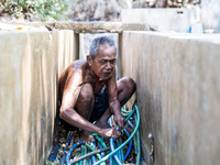 Sarjono (73), an elderly blind man, connects a water hose to the only water source to his house during the drought season in Selopamioro Vil...