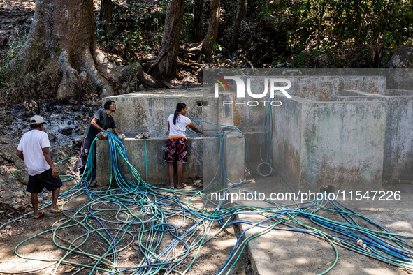 Residents fetch water from the only source by sucking it up and flowing it through a hose to their house during the drought season in Selopa...