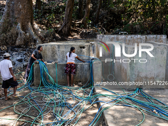 Residents fetch water from the only source by sucking it up and flowing it through a hose to their house during the drought season in Selopa...