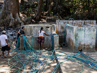 Residents fetch water from the only source by sucking it up and flowing it through a hose to their house during the drought season in Selopa...