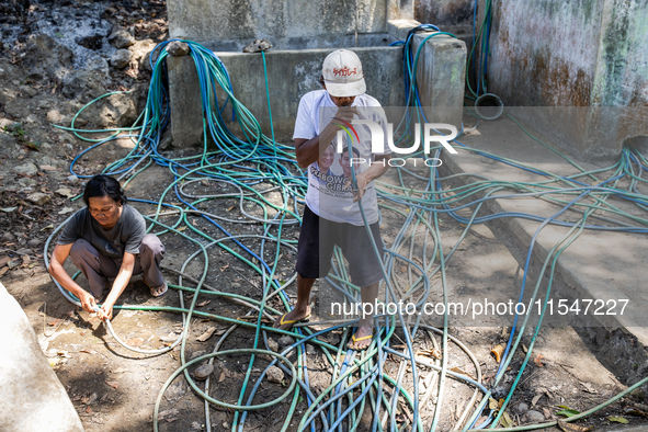 Residents fetch water from the only source by sucking it up and flowing it through a hose to their house during the drought season in Selopa...