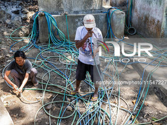 Residents fetch water from the only source by sucking it up and flowing it through a hose to their house during the drought season in Selopa...