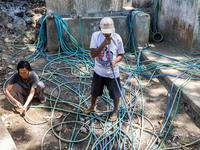 Residents fetch water from the only source by sucking it up and flowing it through a hose to their house during the drought season in Selopa...