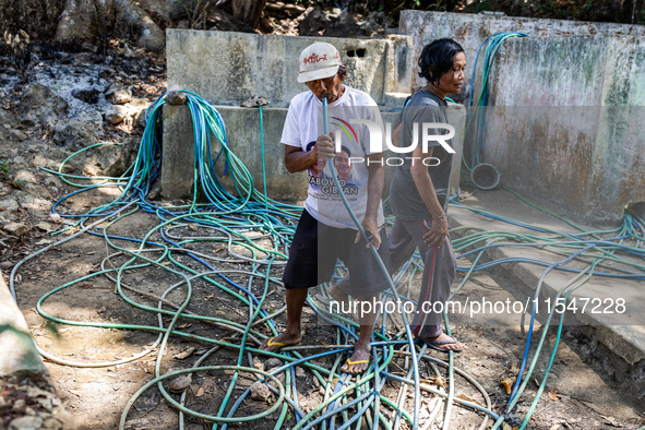 Residents fetch water from the only source by sucking it up and flowing it through a hose to their house during the drought season in Selopa...