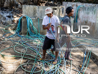 Residents fetch water from the only source by sucking it up and flowing it through a hose to their house during the drought season in Selopa...