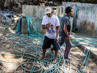 Residents fetch water from the only source by sucking it up and flowing it through a hose to their house during the drought season in Selopa...