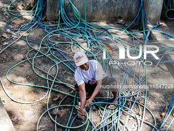 A man takes water from the only source of water by sucking it up and flowing it through a hose to his house during drought season in Selopam...