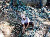 A man takes water from the only source of water by sucking it up and flowing it through a hose to his house during drought season in Selopam...