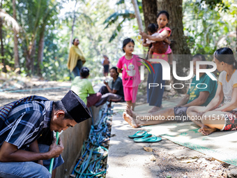 Residents fetch water from the only source by sucking it up and flowing it through a hose to their house during the drought season in Selopa...