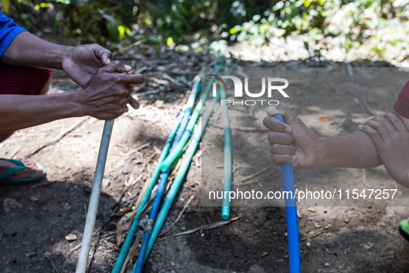 Residents hold a water hose before flowing it to their house during drought season in Selopamioro Village, Bantul Regency, Yogyakarta Provin...