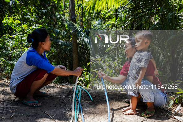 Residents hold a water hose before flowing it to their house during drought season in Selopamioro Village, Bantul Regency, Yogyakarta Provin...