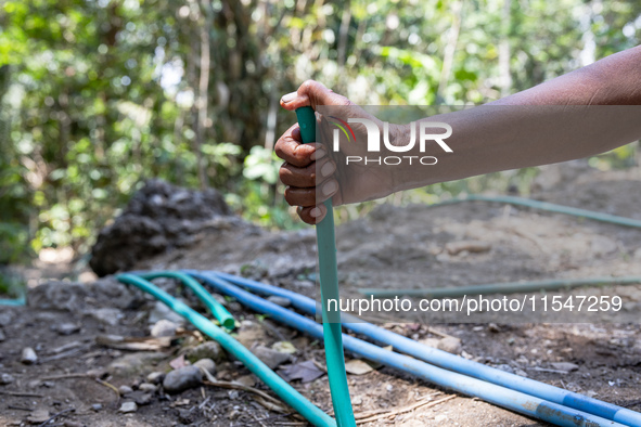 A woman holds a water hose before flowing it to her house during drought season in Selopamioro Village, Bantul Regency, Yogyakarta Province,...