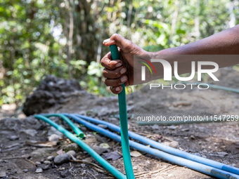 A woman holds a water hose before flowing it to her house during drought season in Selopamioro Village, Bantul Regency, Yogyakarta Province,...