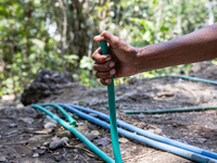 A woman holds a water hose before flowing it to her house during drought season in Selopamioro Village, Bantul Regency, Yogyakarta Province,...