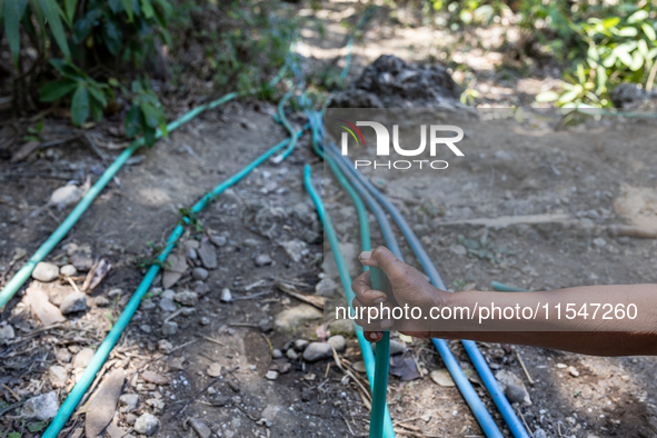 A woman holds a water hose before flowing it to her house during drought season in Selopamioro Village, Bantul Regency, Yogyakarta Province,...