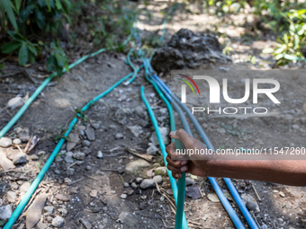 A woman holds a water hose before flowing it to her house during drought season in Selopamioro Village, Bantul Regency, Yogyakarta Province,...