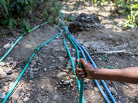 A woman holds a water hose before flowing it to her house during drought season in Selopamioro Village, Bantul Regency, Yogyakarta Province,...