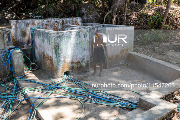 Sarjono (73), an elderly blind man, walks to connect a water hose to his house during the drought season in Selopamioro Village, Bantul Rege...