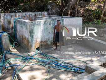 Sarjono (73), an elderly blind man, walks to connect a water hose to his house during the drought season in Selopamioro Village, Bantul Rege...