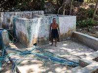 Sarjono (73), an elderly blind man, walks to connect a water hose to his house during the drought season in Selopamioro Village, Bantul Rege...