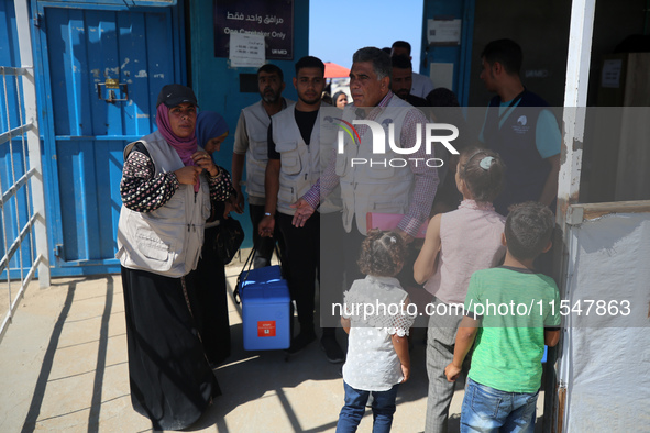 Health workers carry containers filled with polio vaccines during a vaccination campaign at the UK-MED field hospital in Khan Younis in the...