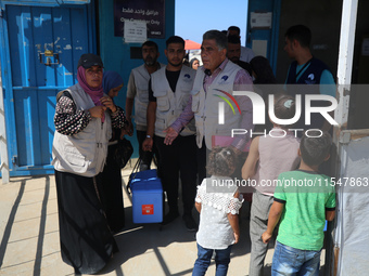 Health workers carry containers filled with polio vaccines during a vaccination campaign at the UK-MED field hospital in Khan Younis in the...