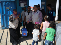 Health workers carry containers filled with polio vaccines during a vaccination campaign at the UK-MED field hospital in Khan Younis in the...