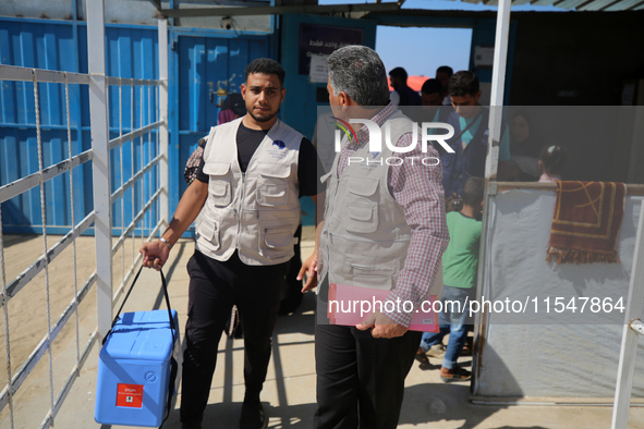 Health workers carry containers filled with polio vaccines during a vaccination campaign at the UK-MED field hospital in Khan Younis in the...